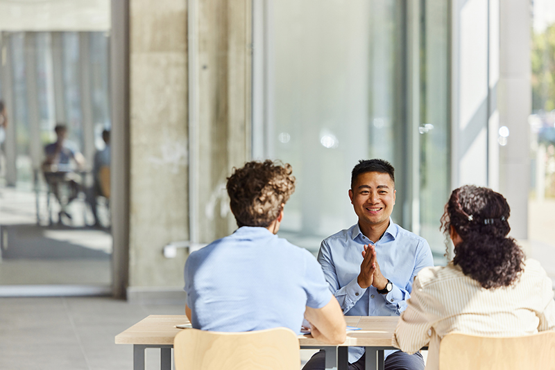 Happy Asian agent talking to his customers in the office.